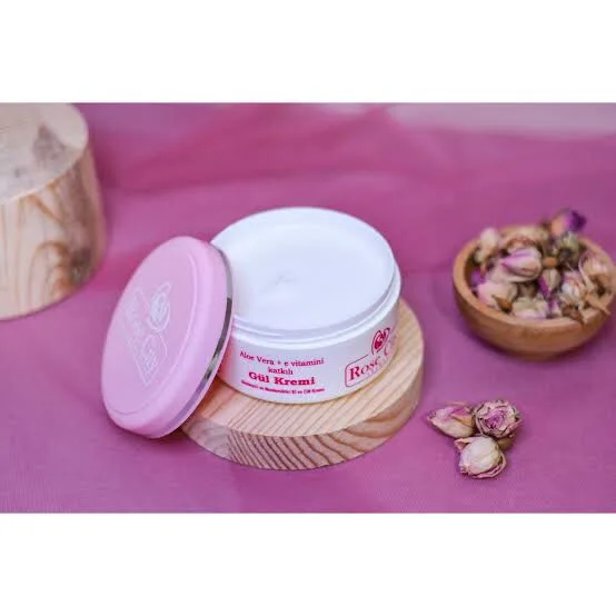 Pembe kapaklı yüz kremi kavanozu ve kuru gül tomurcukları